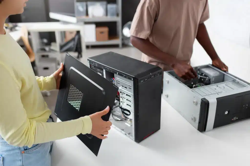 Pessoas realizando manutenção em computadores desktop para ampliar a vida útil de equipamentos de TI.